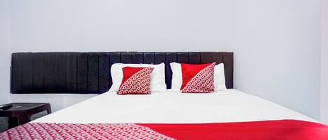 A bed with a white and red patterned bedspread, two pillows with a red and white pattern, and a dark headboard.
