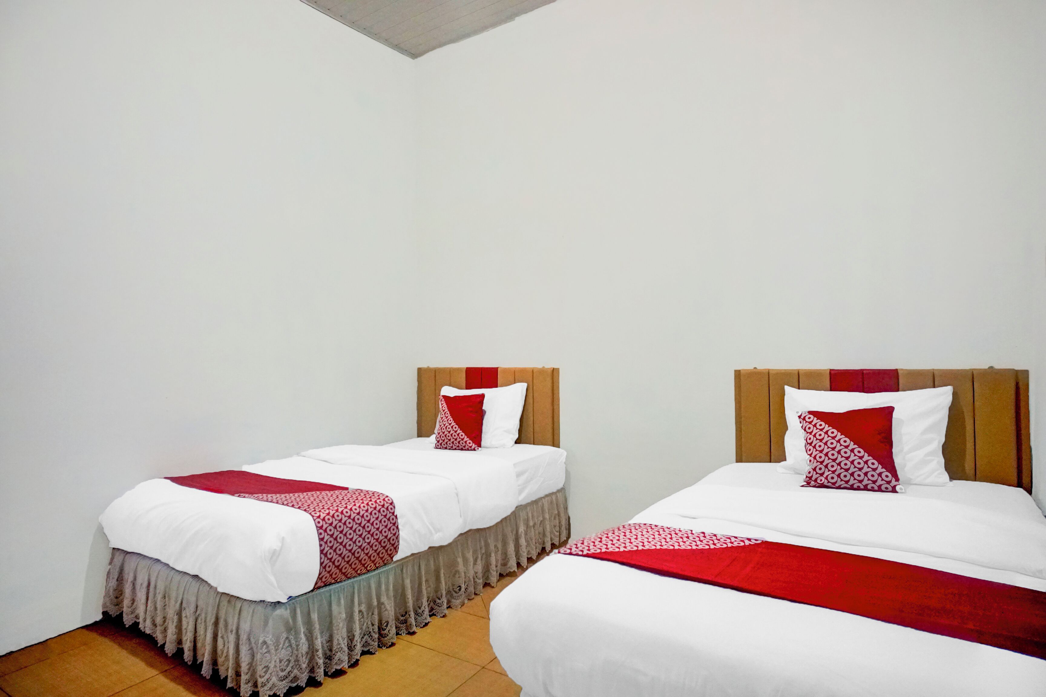 Two single beds with wooden headboards, white bedding, and red accents.