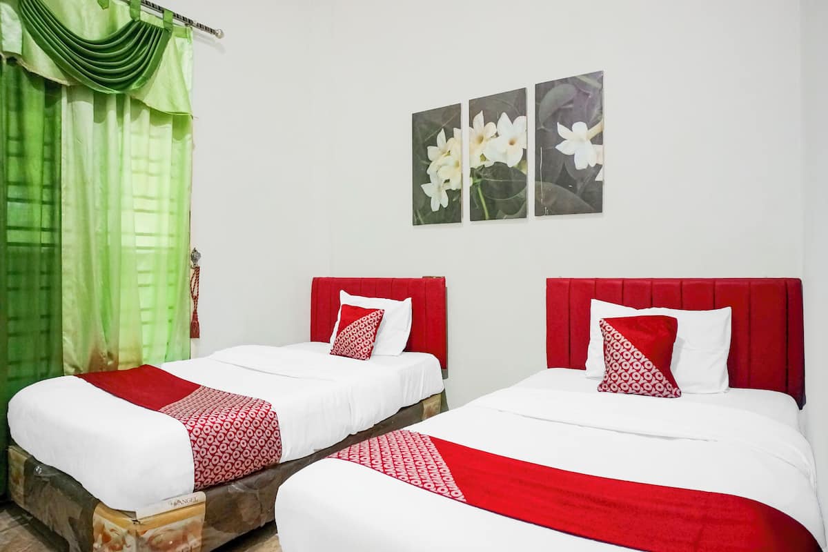 Two twin beds with red and white bedding, a green curtain, and a wall with three flower paintings.