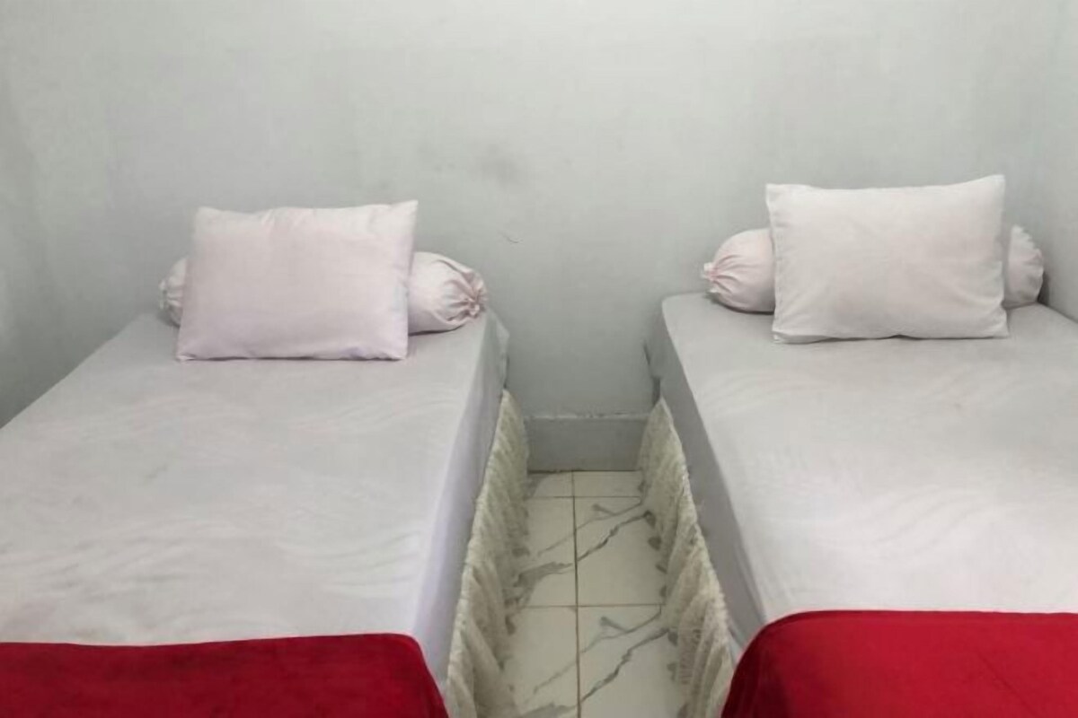 Two single beds with white bedding and red footrests, separated by a narrow gap.