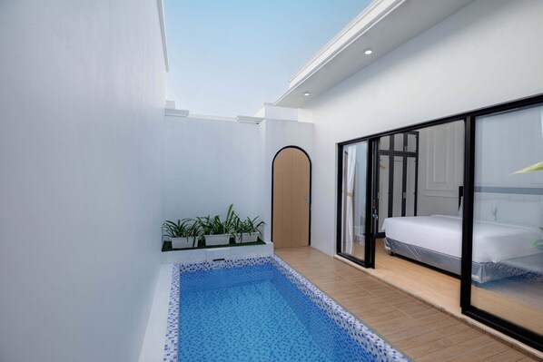 A modern hotel room with a large window, a small pool, and a bed with a view.