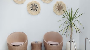 Ein Zimmer mit zwei Korbstühlen, einem kleinen runden Tisch und einer Topfpflanze.