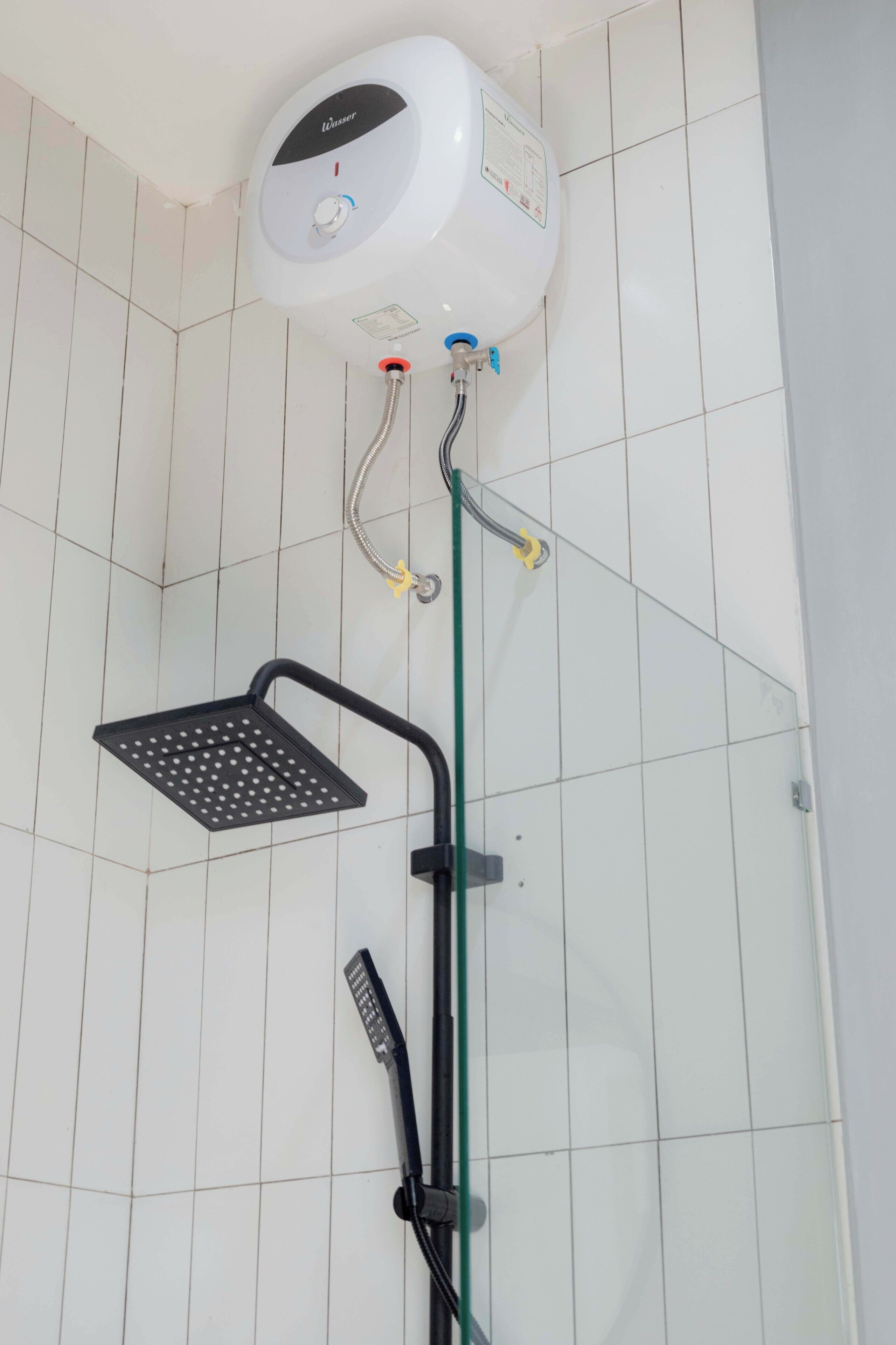 A shower with a control panel, a handheld showerhead, and a floor-mounted showerhead.