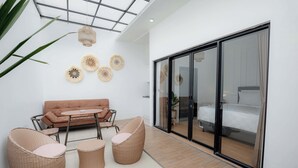 Ein modernes Interieur mit einer Couch, zwei Korbstühlen, einem kleinen Tisch und Wanddekoration.