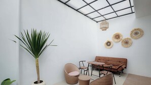 Ein moderner Außenbereich mit Korbmöbeln, einem Blumentopf und dekorativen Wandgestaltungen.