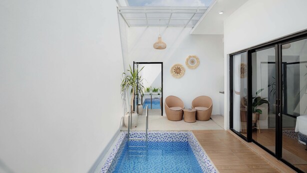 Ein modernes Interieur mit Pool, Korbmöbeln und einer Glastür, die auf einen Balkon führt.