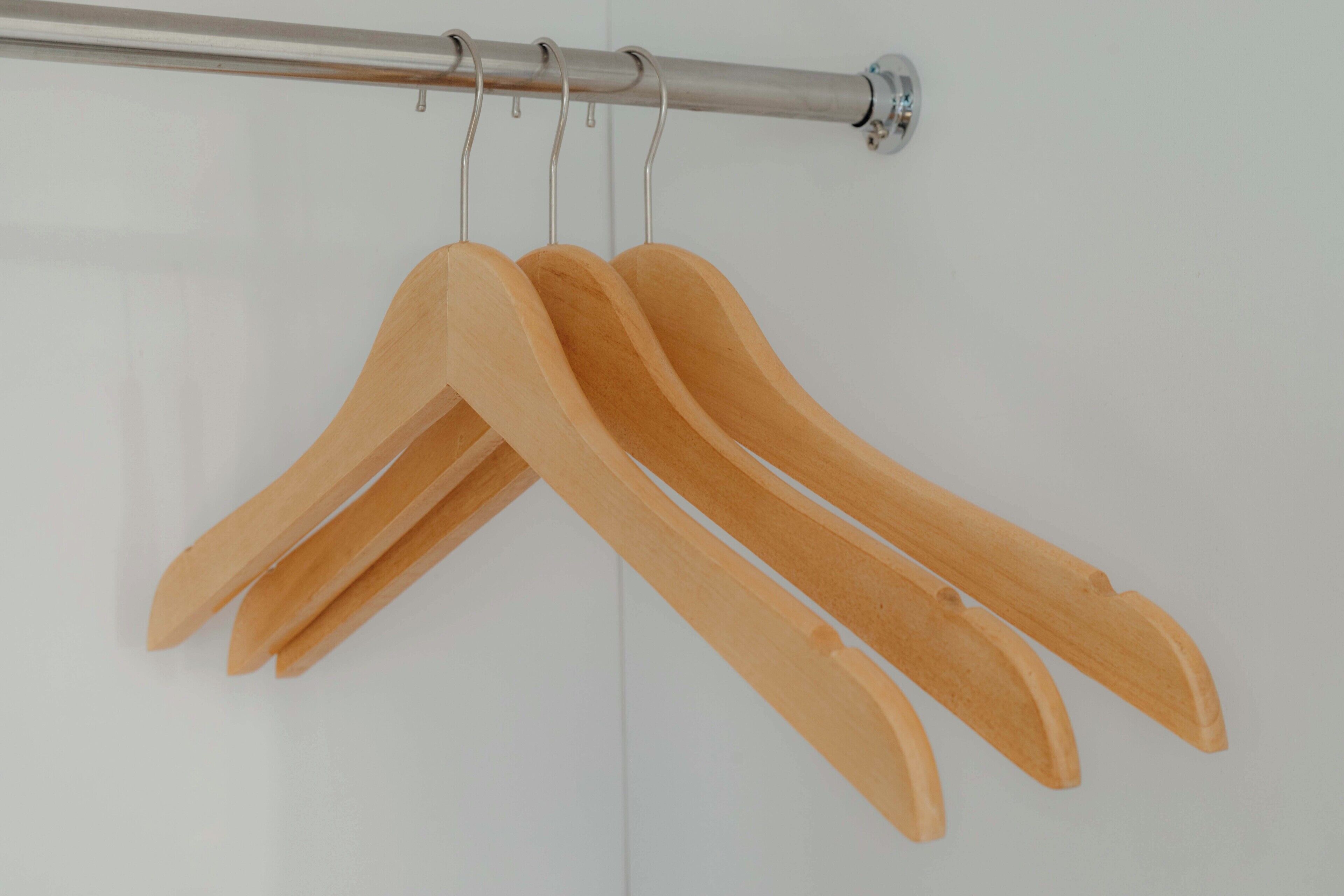A metal curtain rod with wooden hangers.