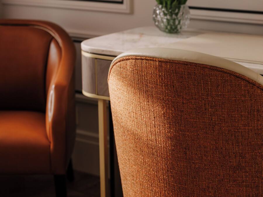 A dining area with a brown leather chair, a white table, and a vase with white flowers.