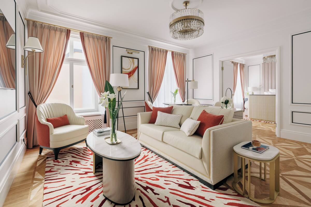 A modern living room with a sofa, armchairs, a coffee table, and a chandelier.