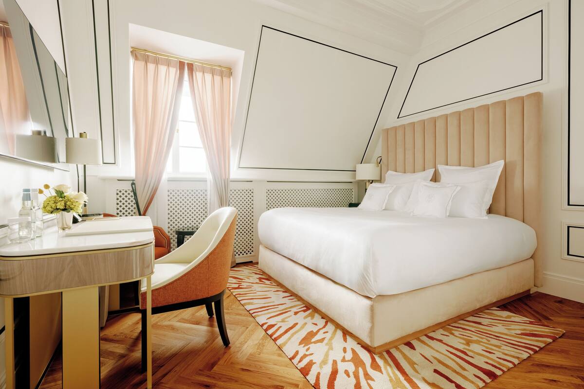 A modern bedroom with a large bed, a bedside table, a chair, and a mirror.