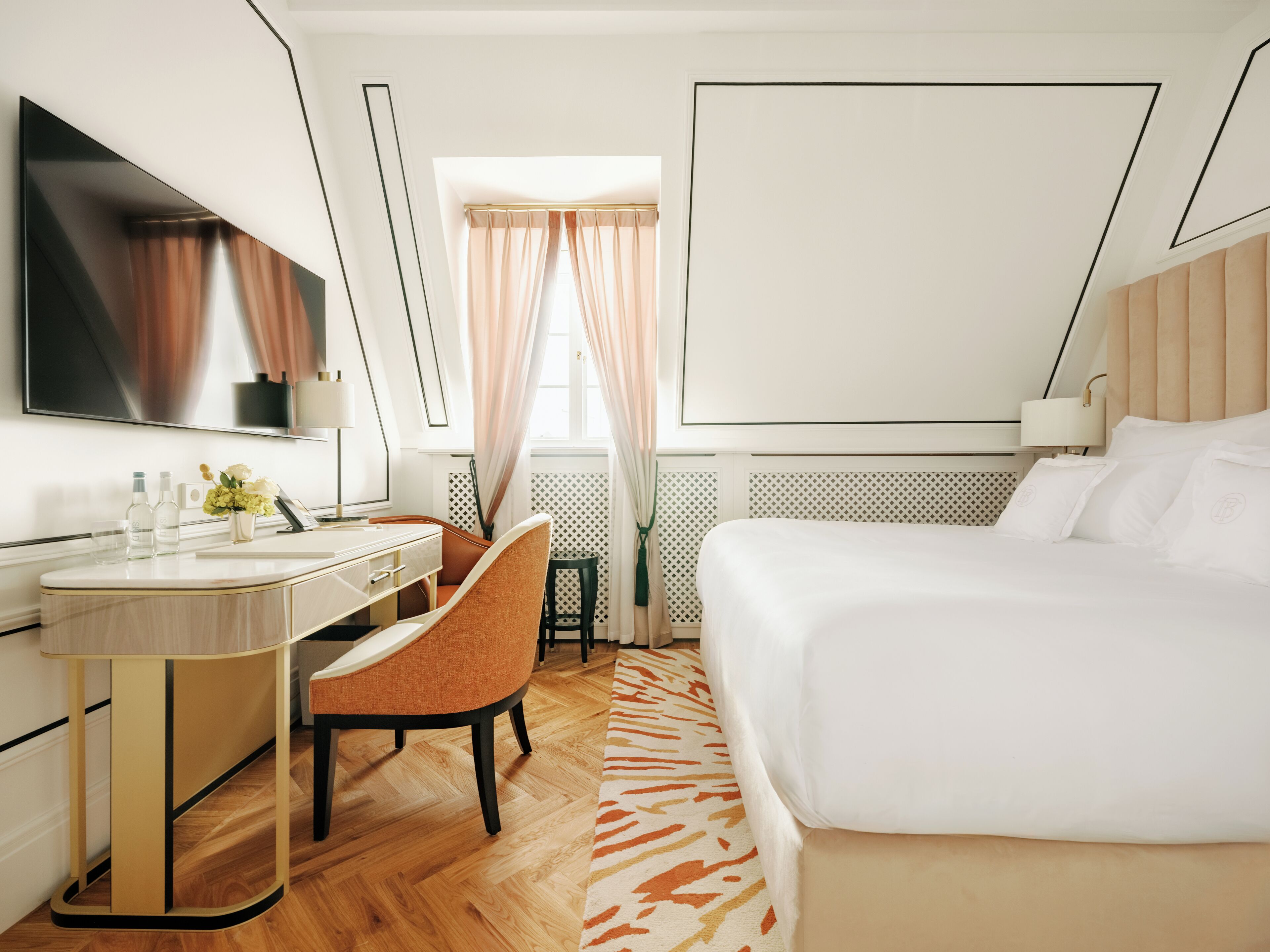 Une chambre d’hôtel moderne équipée d’un grand lit, d’un bureau avec une chaise, d’une coiffeuse et d’un téléviseur.