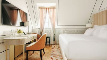 Une chambre d’hôtel moderne équipée d’un grand lit, d’un bureau avec une chaise, d’une coiffeuse et d’un téléviseur.