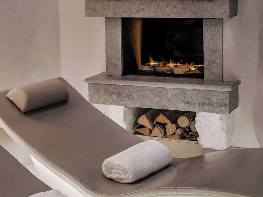 A spa area with a stone fireplace, a massage table, and a towel.