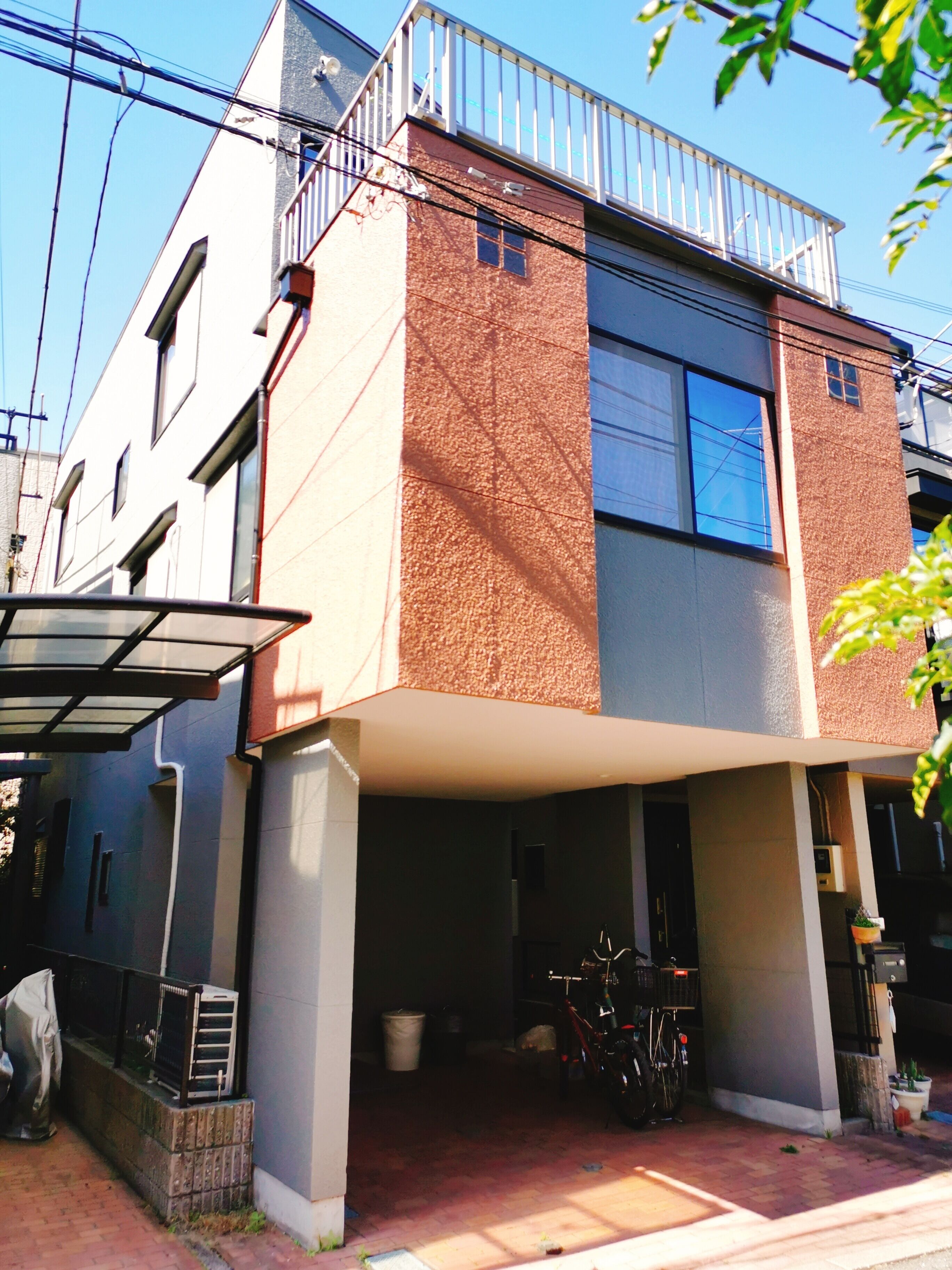 A modern two-story building with a covered entrance and a bicycle parked outside.