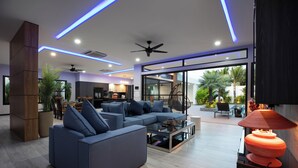 Un salon moderne avec un canapé d’angle, une table basse en verre et un ventilateur de plafond.