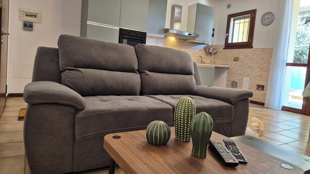 Una sala de estar con un sofá gris, una mesa de centro de madera y jarrones decorativos.