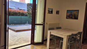 Habitación con puerta de vidrio corredera que da a un espacio exterior, una mesa de madera con sillas y un radiador en la pared.
