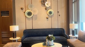 A modern living room with a blue sofa, two armchairs, a coffee table, and decorative plates on the wall. - Cozy 1-bedroom condo with WiFi, AC near OKADA HOTEL Paranaque (Parañaque)