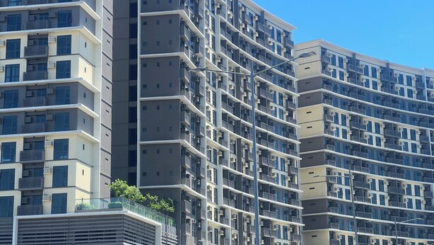 A multi-story residential building with balconies, air conditioning units, and a clear blue sky. - Cozy 1-bedroom condo with WiFi, AC near OKADA HOTEL Paranaque (Parañaque)