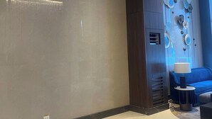 A modern hotel lobby with a marble floor, a blue sofa, and a wall-mounted light fixture. - Cozy 1-bedroom condo with WiFi, AC near OKADA HOTEL Paranaque (Parañaque)