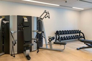 Et træningscenter med styrkemaskiner, håndvægte og en bænk.