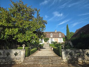 A stone pathway leading to a traditional building with a tiled roof, surrounded by greenery and a clear sky. - Typical mansion with pool in a haven of peace (Liorac-sur-Louyre)