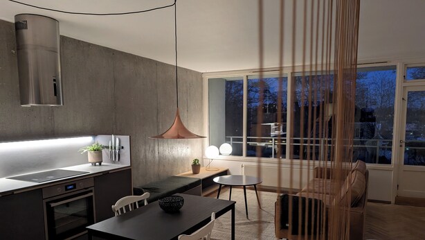 Une cuisine moderne dotée d’un four encastré, un coin repas avec une table et des chaises, et une grande fenêtre offrant une vue sur l’extérieur.