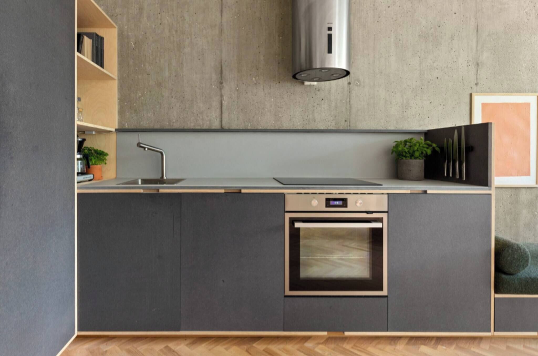 Una cocina moderna con horno empotrado, campana extractora de acero inoxidable y paneles de madera.