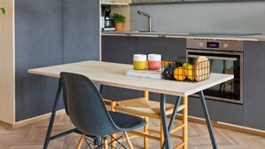 A modern kitchen with a wooden table, black chairs, and a hanging pendant light. - NYC Studio in Central Oslo (Oslo)