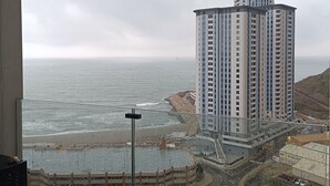 Een hoog gebouw met uitzicht op zee en een bouwterrein eronder.