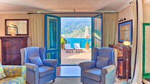Une pièce avec deux fauteuils placés face à un balcon d’où l’on peut admirer la mer.