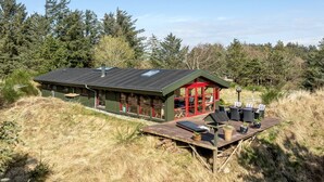 A cabin with a deck, large windows, and a red door. - "Nimrod" - 800m from the sea by Interhome (Blokhus)