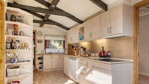 A compact kitchen with white cabinets, a wooden ceiling, and a window with a view of greenery. - "Nimrod" - 800m from the sea by Interhome (Blokhus)