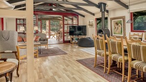 A spacious living room with a high ceiling, wooden beams, a fireplace, and a TV. - "Nimrod" - 800m from the sea by Interhome (Blokhus)