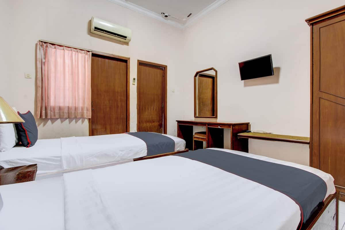Une chambre d’hôtel avec deux lits, un bureau, une chaise, une télévision et un appareil de climatisation.