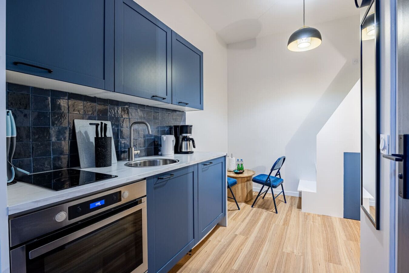 A modern kitchen with dark blue cabinets, a white countertop, a built-in oven, and a coffee maker.
