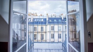 A view from a window with a metal railing, looking out onto a courtyard with buildings in the background. - Studio FullEquiped 2person with balcony 17th (Paris)