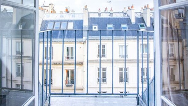 A view from a balcony with a clear sky, featuring traditional European buildings with multiple stories and visible chimneys. - Studio FullEquiped 2person with balcony 17th (Paris)