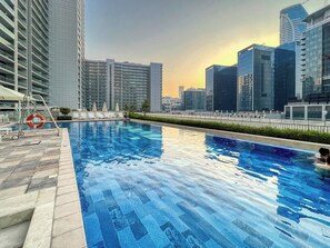 Ein Pool auf dem Dach mit Blick auf die Stadtlandschaft, umgeben von Hochhäusern.