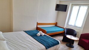 Une chambre d’hôtel avec deux lits, un téléviseur fixé au mur, une petite table ronde et une chaise.