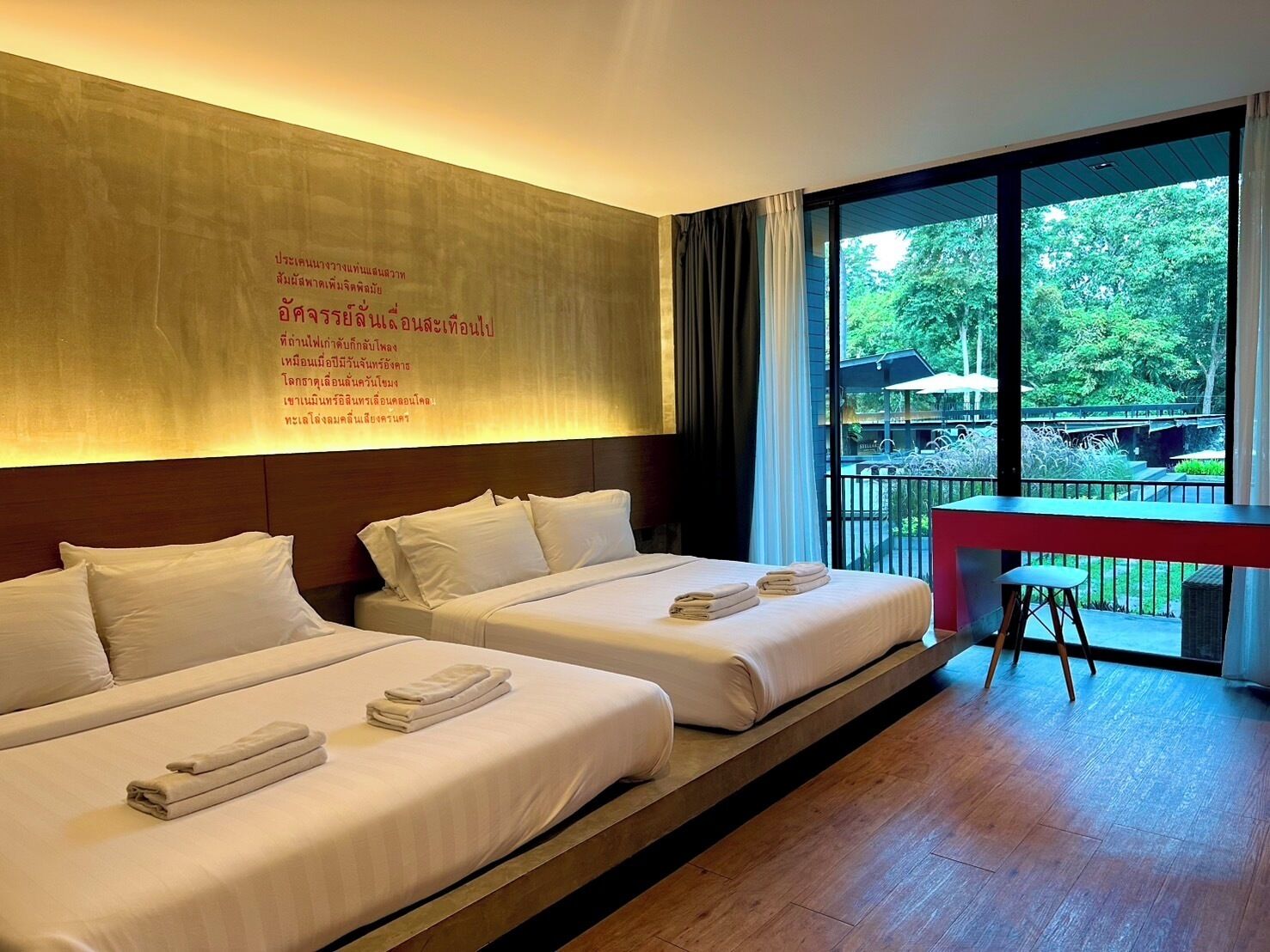 Une chambre d’hôtel avec deux lits, un bureau et une grande fenêtre donnant sur l’extérieur.