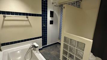 A bathroom with a bathtub, shower, and a towel rack.