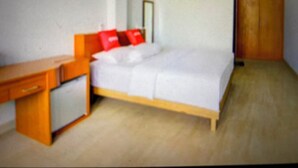 A small, simple room with a bed, a desk, and a wardrobe. - OYO 94316 BPG (Banda Aceh)
