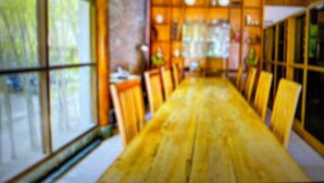 A dining area with a long wooden table and chairs, large windows, and a wooden ceiling. - OYO 94316 BPG (Banda Aceh)
