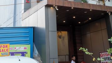 A hotel named "MADHAPALACE" with a modern facade, large windows, and a visible entrance.