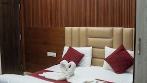 Quarto de hotel com uma cama grande, painéis de madeira nas paredes e um ventilador de teto.