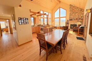 A spacious kitchen with wooden cabinets, a large dining table, and a stone fireplace.