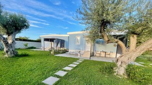 A modern house with a covered patio, a well-maintained lawn, and a stone pathway leading to the entrance. - Anastasia beach cottage Sunflower (Siracusa)