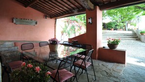 An outdoor patio with a glass table and chairs, surrounded by stone walls and potted plants. - Elegante villa con piscina a soli 12 km da Firenze ideale per famiglie e gruppi (Toscana)