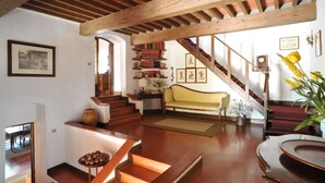 A spacious living area with a wooden staircase, a sofa, a coffee table, and a bookshelf. - Elegante villa con piscina a soli 12 km da Firenze ideale per famiglie e gruppi (Toscana)
